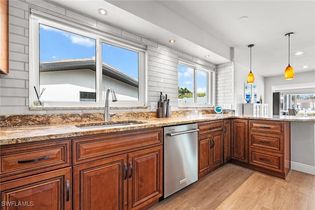 kitchen featuring pendant lighting, decorative backsplash, sink, light wood-type flooring, and light stone countertops