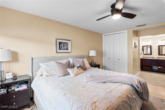 bedroom with ceiling fan, connected bathroom, a closet, and light hardwood / wood-style flooring