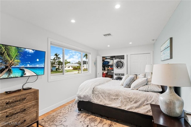 bedroom featuring stacked washing maching and dryer and light hardwood / wood-style floors