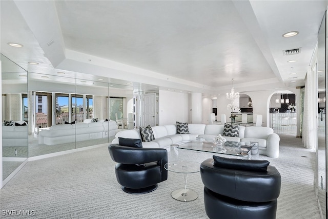 carpeted living room featuring a raised ceiling and a notable chandelier