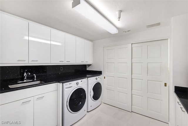 laundry area featuring separate washer and dryer, cabinets, and sink