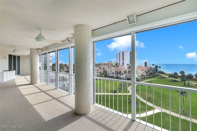 unfurnished sunroom with ceiling fan and a water view