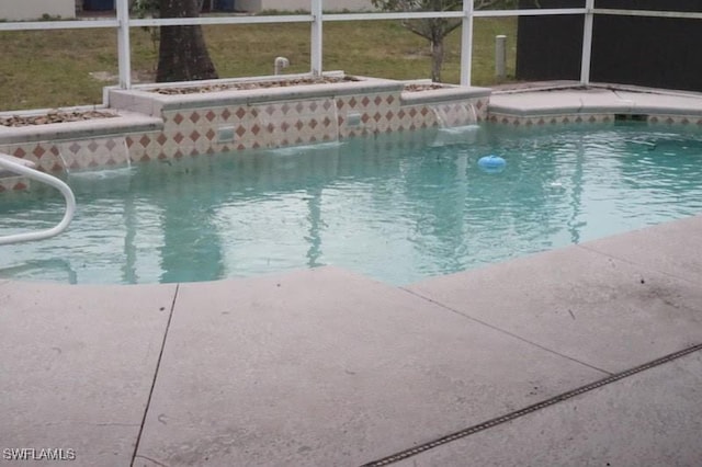 view of pool with glass enclosure, pool water feature, and a jacuzzi