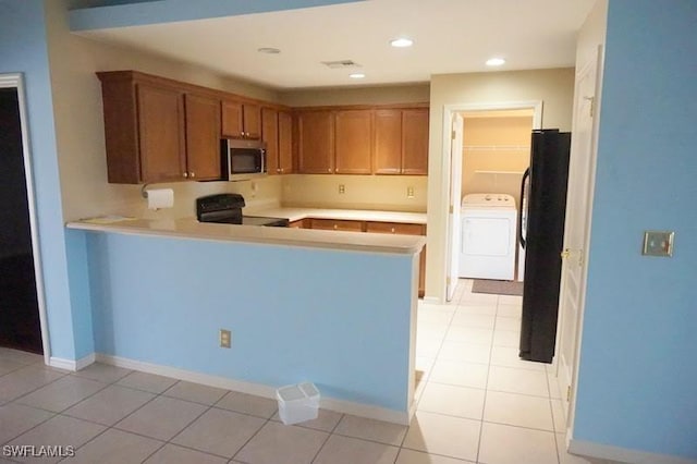 kitchen with black appliances, washer / dryer, kitchen peninsula, and light tile patterned floors