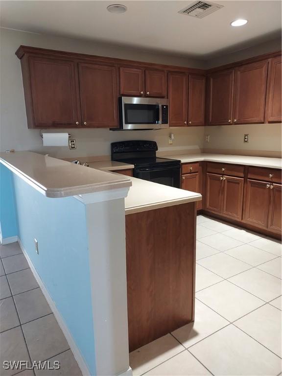 kitchen featuring black / electric stove, light tile patterned floors, and kitchen peninsula