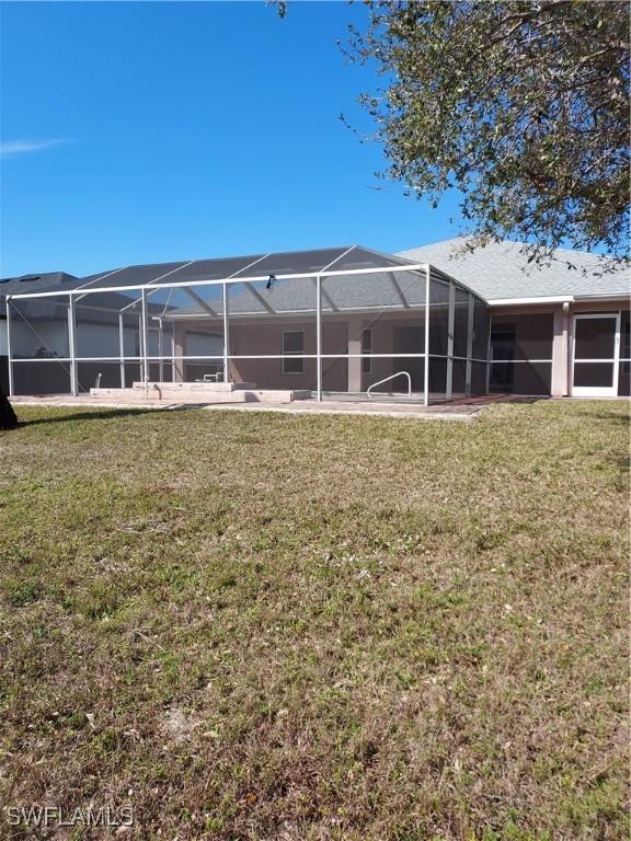 back of house with a yard and glass enclosure