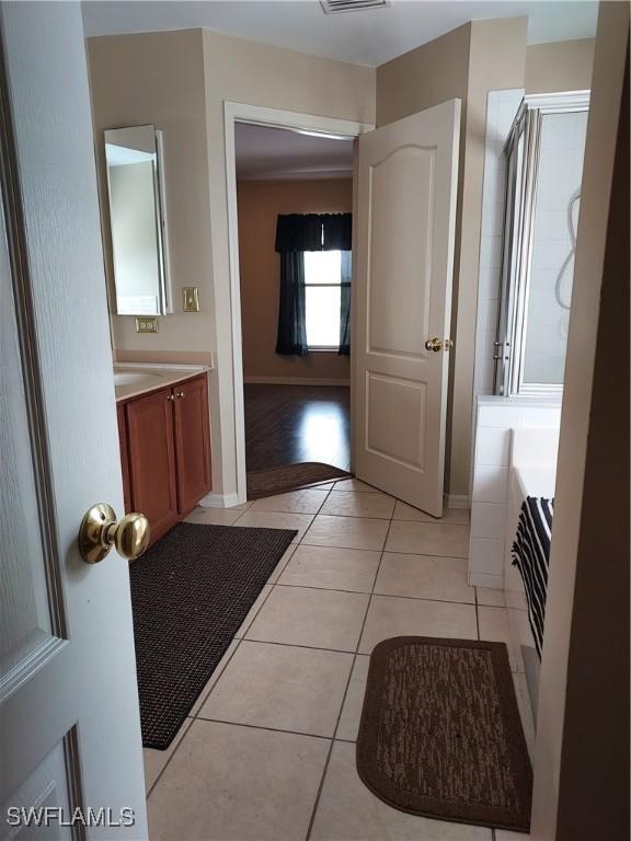 bathroom featuring tile patterned flooring, vanity, and walk in shower