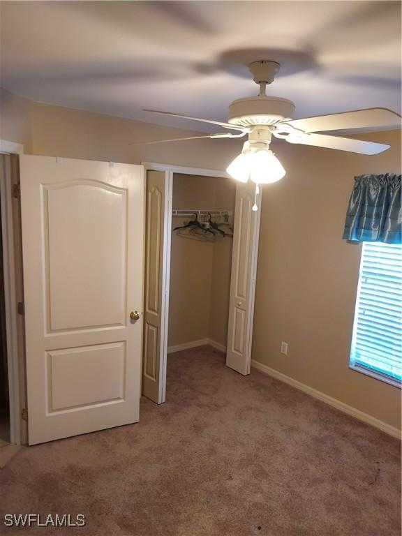 unfurnished bedroom featuring light carpet, ceiling fan, and a closet