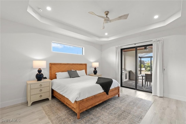 bedroom with light hardwood / wood-style floors, a raised ceiling, access to outside, and ceiling fan