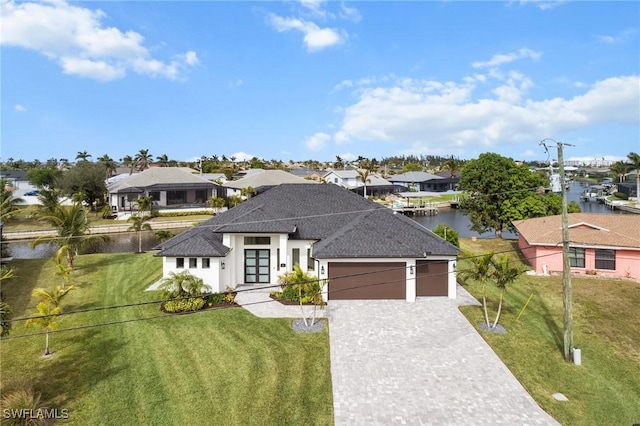 view of front of property featuring a front yard, a water view, french doors, and a garage