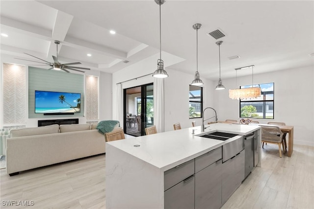 kitchen featuring dishwasher, pendant lighting, gray cabinetry, and an island with sink