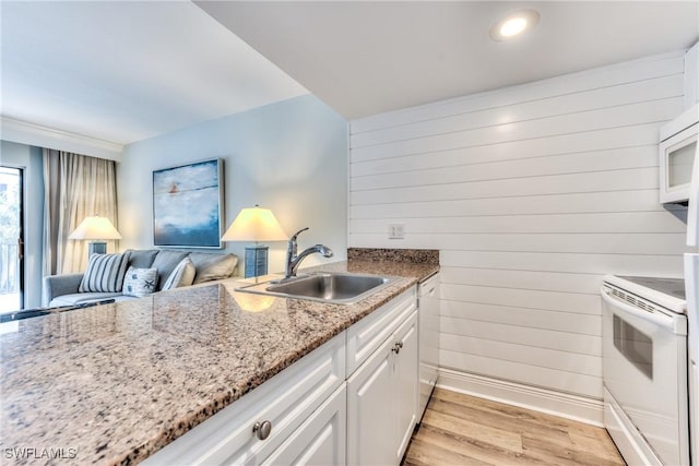 kitchen featuring white appliances, light wood-type flooring, light stone countertops, white cabinets, and sink