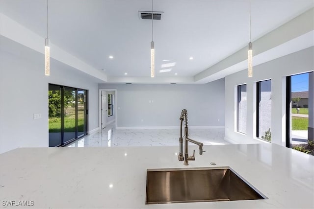 kitchen with light stone countertops, decorative light fixtures, and sink