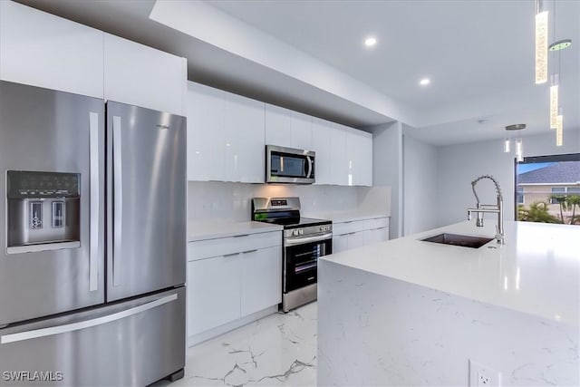 kitchen featuring decorative light fixtures, sink, white cabinetry, and appliances with stainless steel finishes