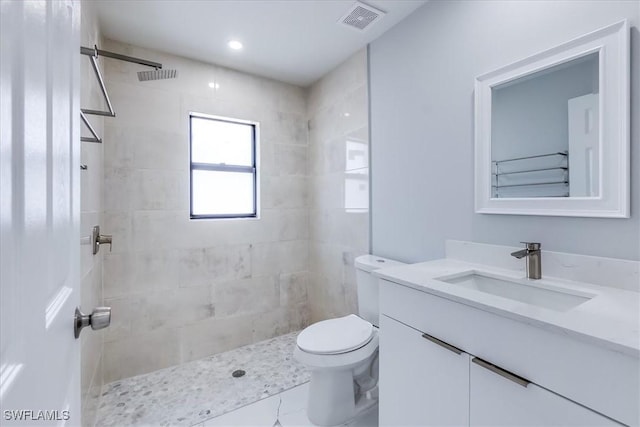 bathroom featuring toilet, vanity, and tiled shower