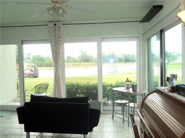 sunroom featuring a water view and ceiling fan