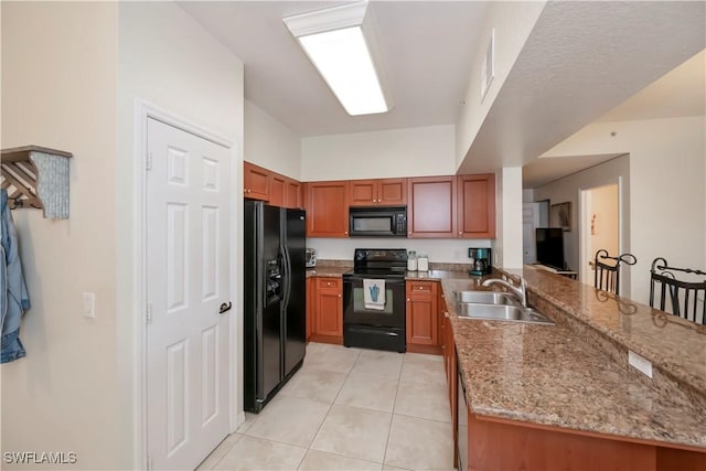 kitchen with black appliances, sink, kitchen peninsula, light tile patterned flooring, and light stone counters