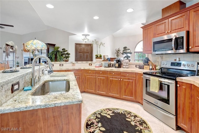 kitchen featuring sink, light tile patterned floors, appliances with stainless steel finishes, tasteful backsplash, and light stone counters