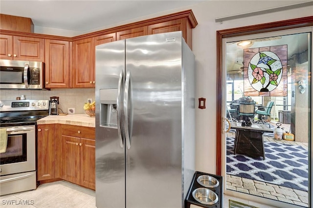 kitchen featuring stainless steel appliances, tasteful backsplash, and light tile patterned floors