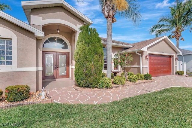 doorway to property with a garage, a yard, and french doors