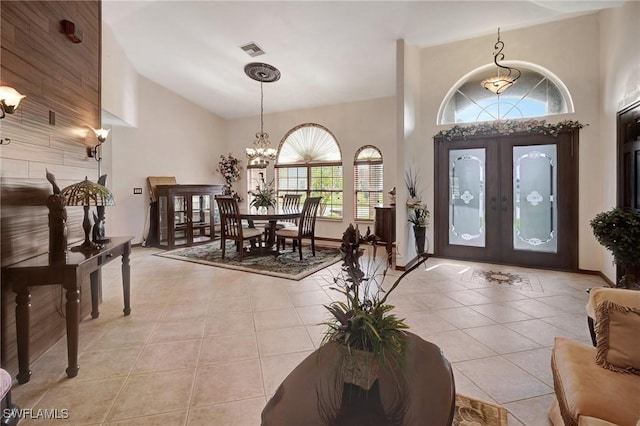 tiled foyer featuring a notable chandelier, high vaulted ceiling, and french doors