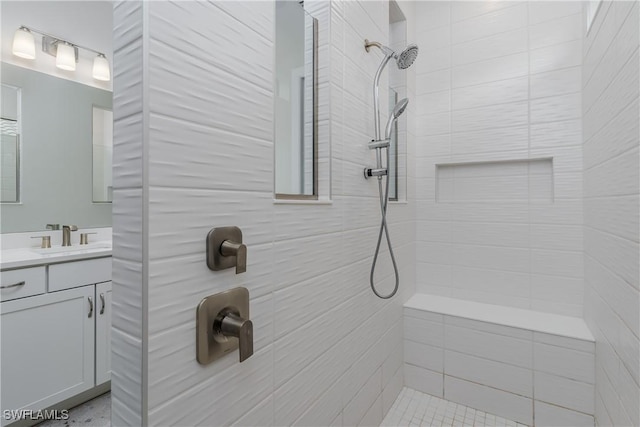 bathroom with tiled shower and vanity