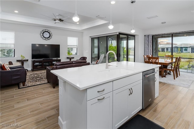 kitchen with sink, white cabinets, decorative light fixtures, ceiling fan, and an island with sink