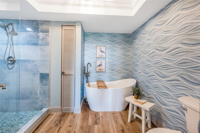 bathroom featuring hardwood / wood-style floors, a skylight, a tray ceiling, shower with separate bathtub, and toilet