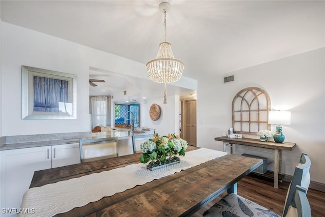 dining room with dark wood-type flooring and ceiling fan with notable chandelier