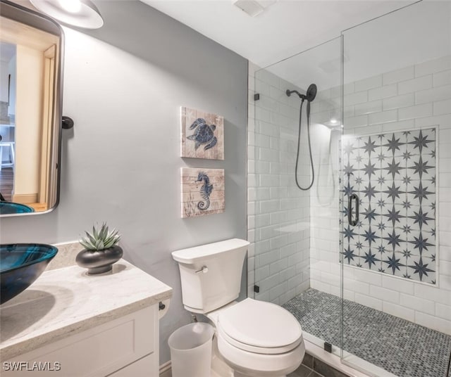 bathroom with vanity, a tile shower, and toilet