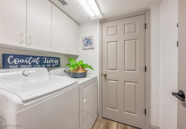 laundry area with cabinets, washing machine and clothes dryer, and light hardwood / wood-style flooring