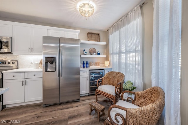 kitchen with white cabinetry, tasteful backsplash, wood-type flooring, stainless steel appliances, and beverage cooler