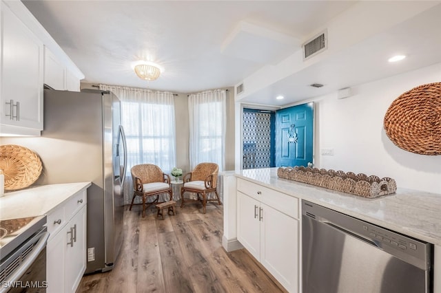 kitchen with white cabinetry, light stone counters, stainless steel appliances, and light hardwood / wood-style floors