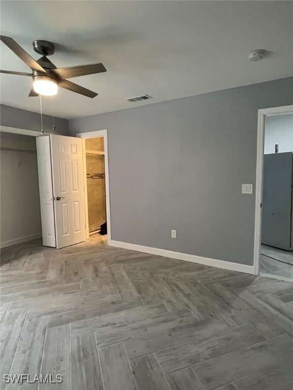 unfurnished bedroom featuring parquet floors, a closet, and ceiling fan