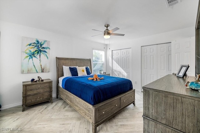 bedroom with multiple closets, visible vents, baseboards, and a ceiling fan