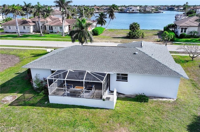 back of house featuring a lanai, a water view, and a lawn