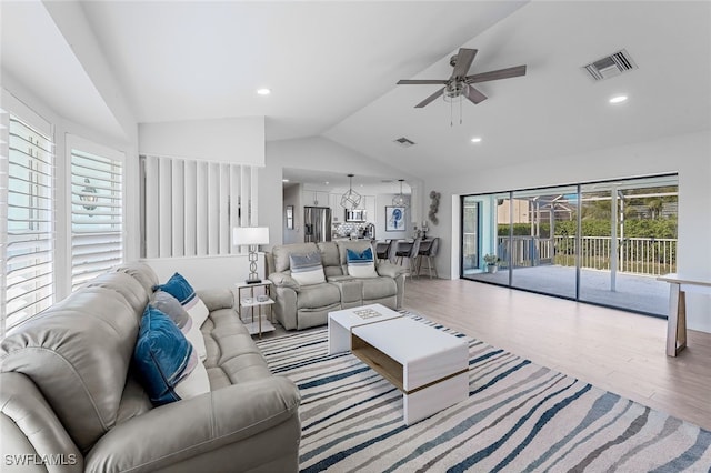 living room with ceiling fan, vaulted ceiling, and light wood-type flooring