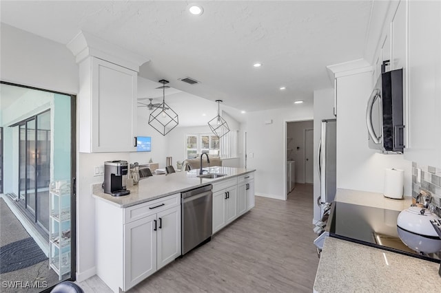 kitchen with decorative light fixtures, white cabinets, appliances with stainless steel finishes, and light stone counters