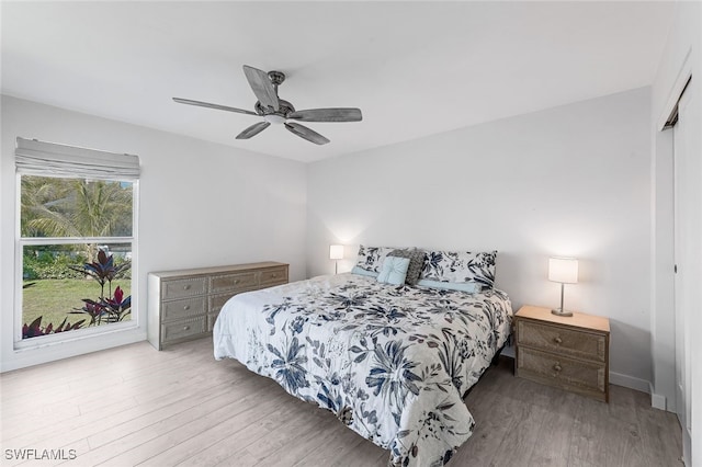 bedroom with light wood-type flooring, ceiling fan, and a closet