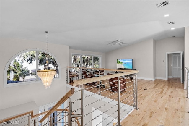 hall with vaulted ceiling, a chandelier, and light hardwood / wood-style flooring