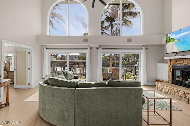 living room featuring light hardwood / wood-style floors, a high ceiling, and a fireplace