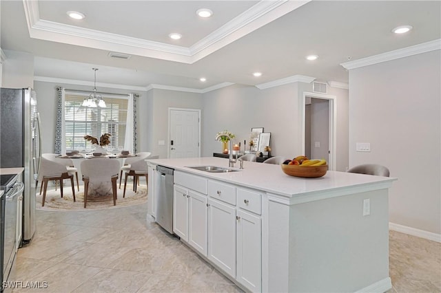 kitchen featuring an island with sink, appliances with stainless steel finishes, decorative light fixtures, white cabinets, and sink