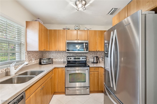 kitchen with light tile patterned floors, sink, appliances with stainless steel finishes, and tasteful backsplash