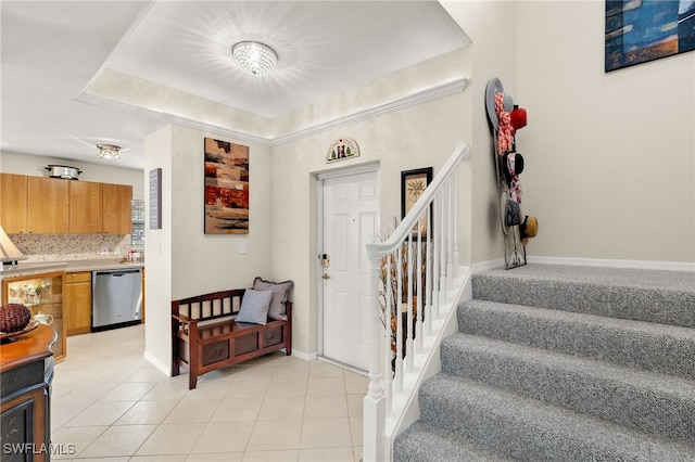 entrance foyer with light tile patterned floors and a tray ceiling