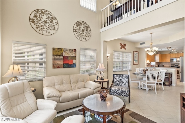 living room with a high ceiling, light tile patterned floors, a wealth of natural light, and an inviting chandelier