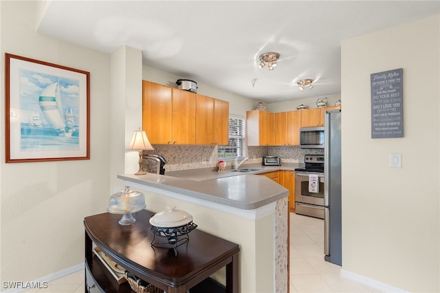 kitchen with tasteful backsplash, kitchen peninsula, sink, a kitchen breakfast bar, and stainless steel appliances