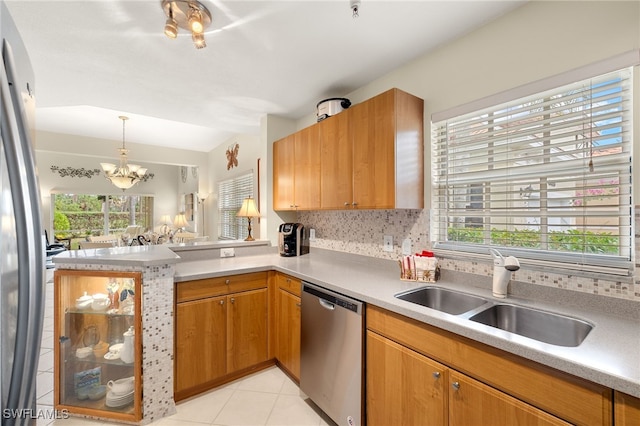 kitchen featuring decorative backsplash, sink, stainless steel appliances, and a notable chandelier