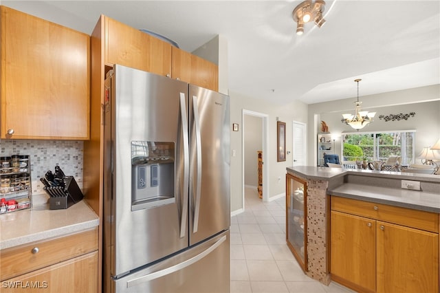 kitchen featuring decorative backsplash, stainless steel fridge, a chandelier, light tile patterned flooring, and light stone counters