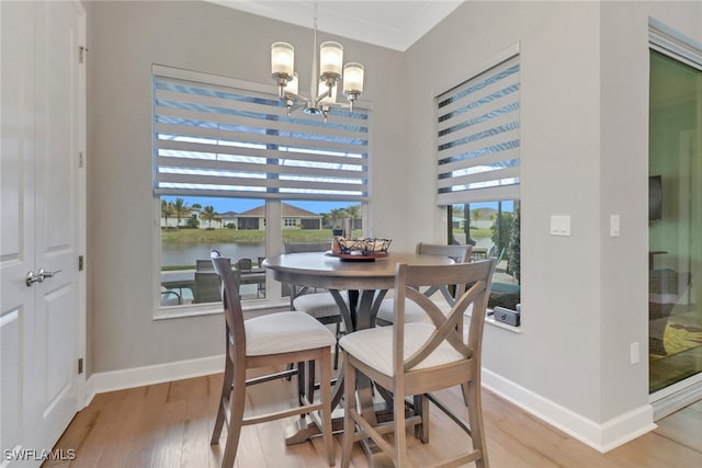 dining room with a water view, wood-type flooring, a notable chandelier, and ornamental molding