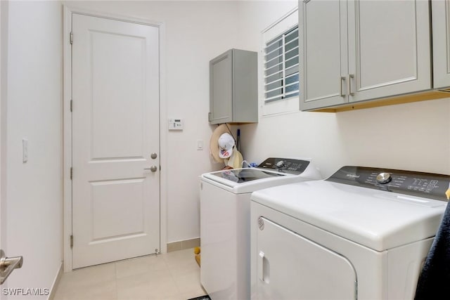 laundry room with light tile patterned floors, cabinets, and washer and clothes dryer